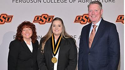 Morgan Pfeiffer stands with Dr. Clary and Dr. Lusk at an awards ceremony.