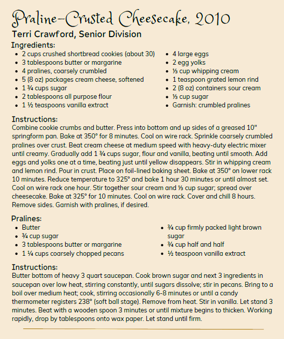 Recipe card titled “Praline-Crusted Cheesecake, 2010” by Terri Crawford, Senior Division. The recipe is displayed on a beige background with black text and includes ingredients and instructions for a cheesecake with a praline crust. Ingredients are listed in two columns and include crushed shortbread cookies, butter, pralines, cream cheese, sugar, flour, vanilla extract, eggs, whipping cream, lemon rind, sour cream, and additional sugar. Detailed baking instructions describe preparing the crust, mixing the filling, baking, cooling, and garnishing with pralines. A second section, labeled “Pralines,” provides ingredients including butter, brown sugar, pecans, half-and-half, and vanilla extract, followed by instructions for cooking a candy mixture and dropping spoonfuls onto wax paper to firm. The page is text-only, with no photographs or illustrations.