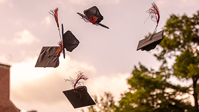 Graduation caps thrown into the air on OSU campus at library lawn.