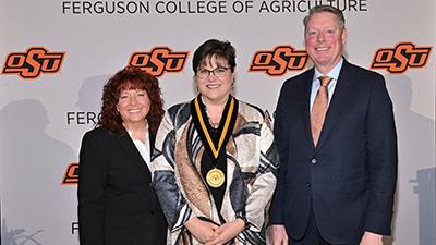 Angel Riggs stands with Dr. Clary and Dr. Lusk at an awards ceremony.