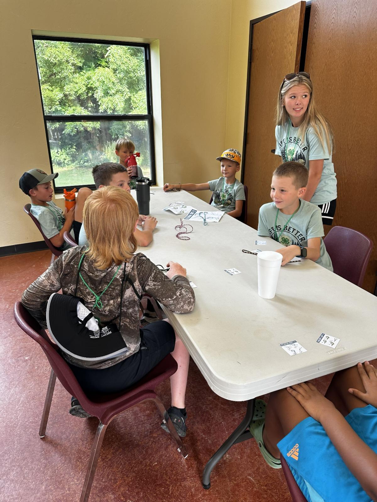 4-H campers participate in a small-group educational activity led by a youth leader, practicing teamwork, communication, and problem-solving during Quad-County 4-H Camp.