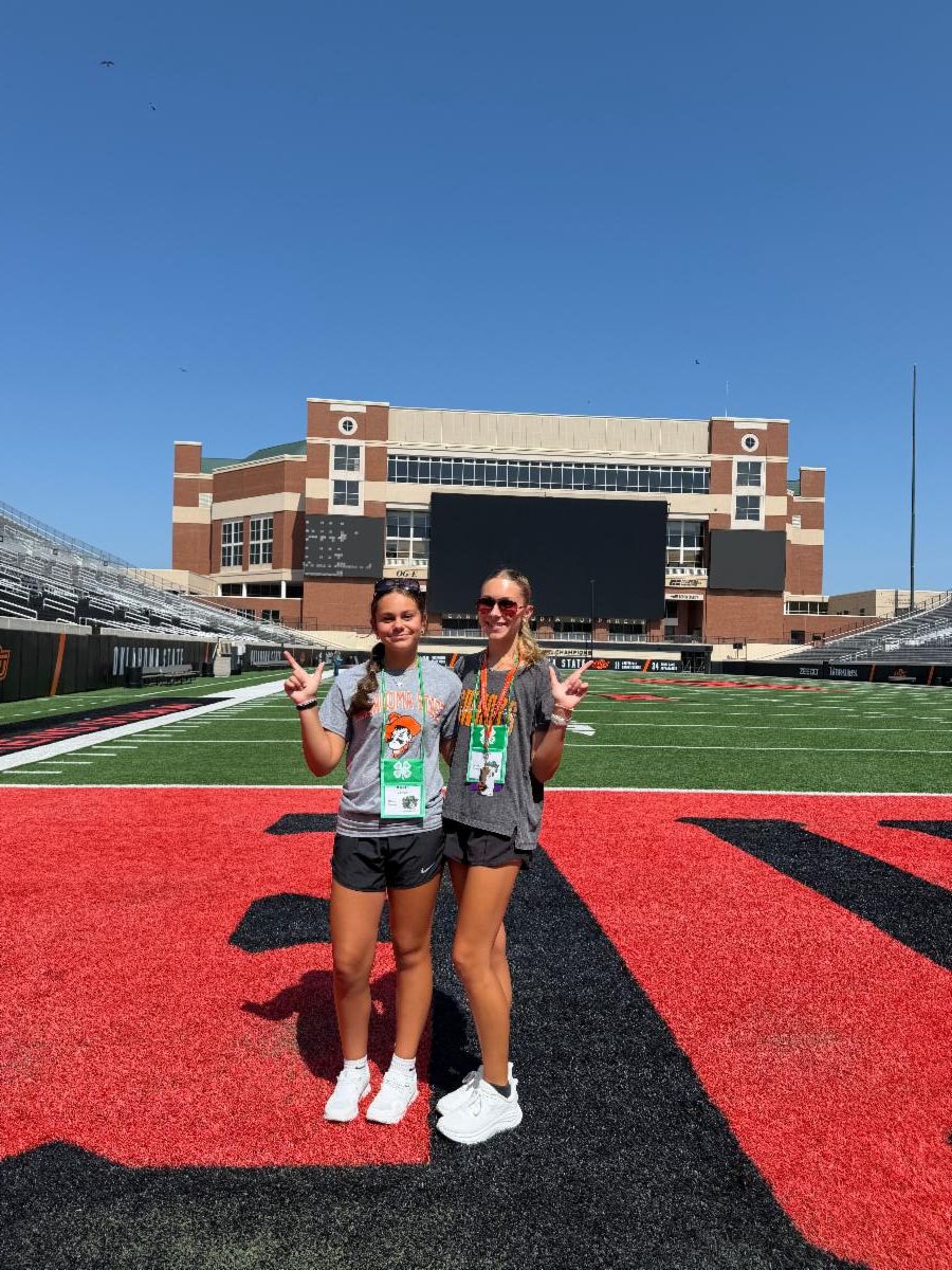 Two 4-H participants pose on the Oklahoma State University football field during a 4-H event, showcasing leadership, learning, and campus experiences.