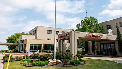 The exterior of a hospital with an emergency room on a sunny day.