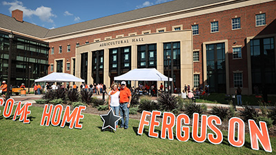 Kayleen and Larry Ferguson stand in front of Ag Hall with a Welcome Home Ferguson sign.