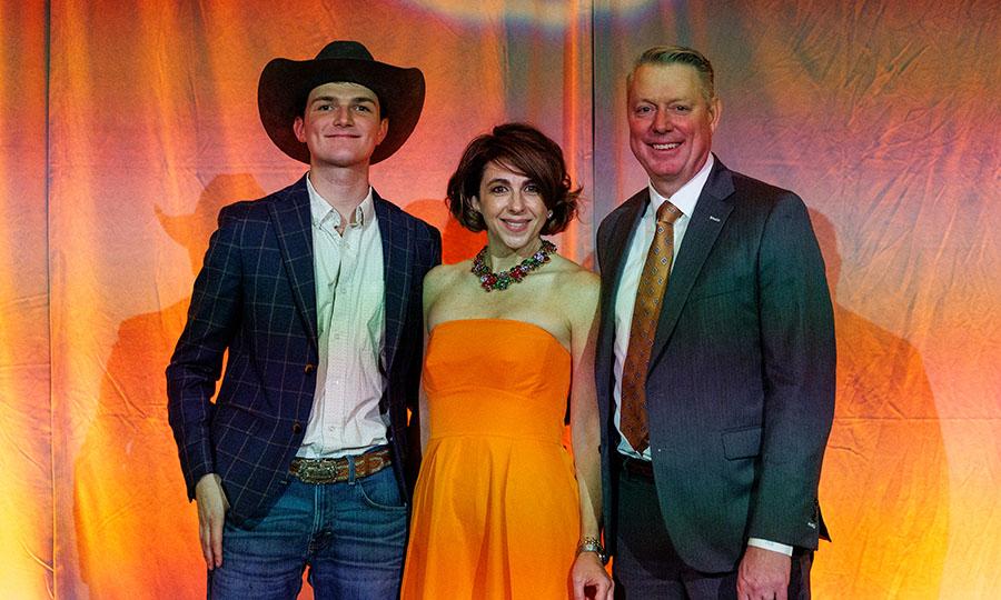 Jayson and Christy Lusk, with son Harrison in front of the orange backdrop at the OSU Agriculture Honors Ceremony.