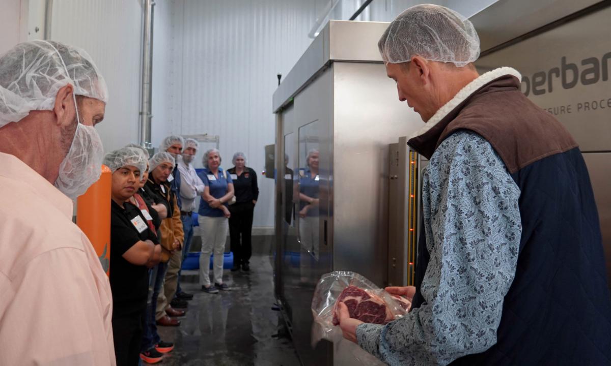 Instructor shows high pressure processed meat cut to workshop attendees in FAPC facilities.