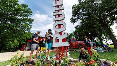 4-H members plant flowers in front of a large Route 66 sign.