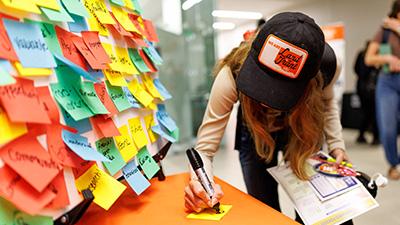 A student writing on a sticky note to add to the land-grant word cloud during Land-Grant Week.