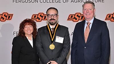 Adel Pezeshki stands with Dr. Clary and Dr. Lusk at an awards ceremony.