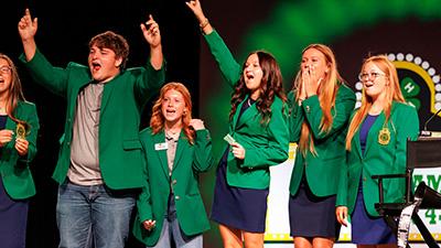4-H members cheering on stage at 4-H Roundup.