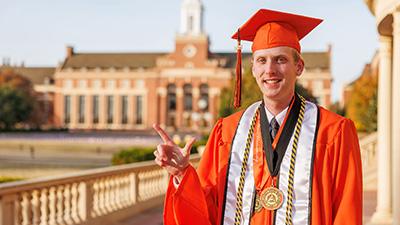 Cody Loganbill in his orange gown and other graduation regalia.