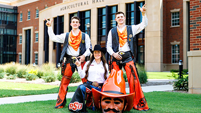 Hunter Morton, Olivia Klug and Pete Littlefield standing outside of Agricultural Hall dressed as Pistol Pete and the Spirit Rider.