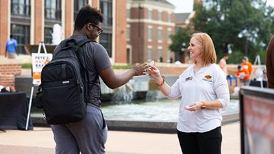 Mandy Gross giving a land-grant sticker to a student during Land-Grant Week.