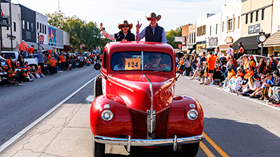 Dr. Jayson Lusk and his wife, Christy Lusk ride in a vintage pickup truck in the OSU homecoming parade.