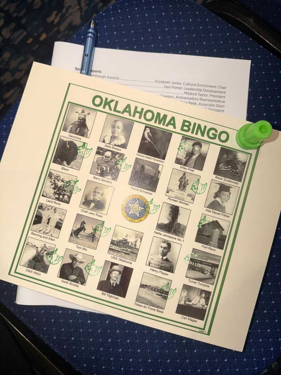 An Oklahoma-themed bingo card, meeting agenda, pen, and bingo marker are displayed at the Oklahoma OHCE Annual Meeting, showcasing a fun educational activity focused on Oklahoma history and culture.