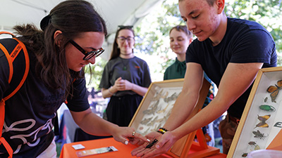 A student touches an insect at the Insect Adventure booth during Land-Grand Week.
