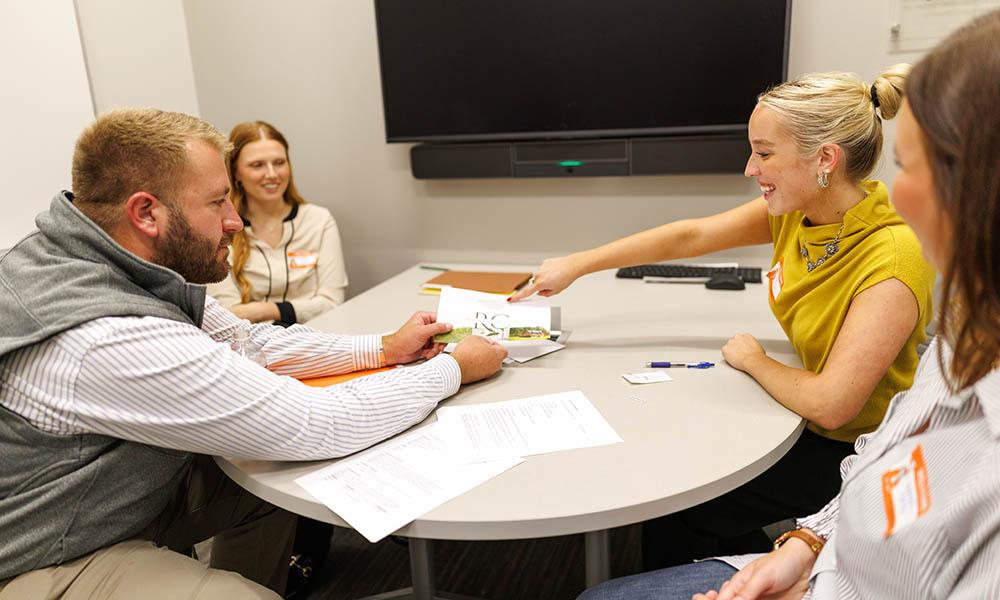 Three students participate in a mock sales call with a real salesperson.