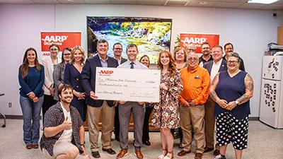 Dr. Brian Whitacre and rural broadband supporters pose with a $5,000 giant check from AARP.
