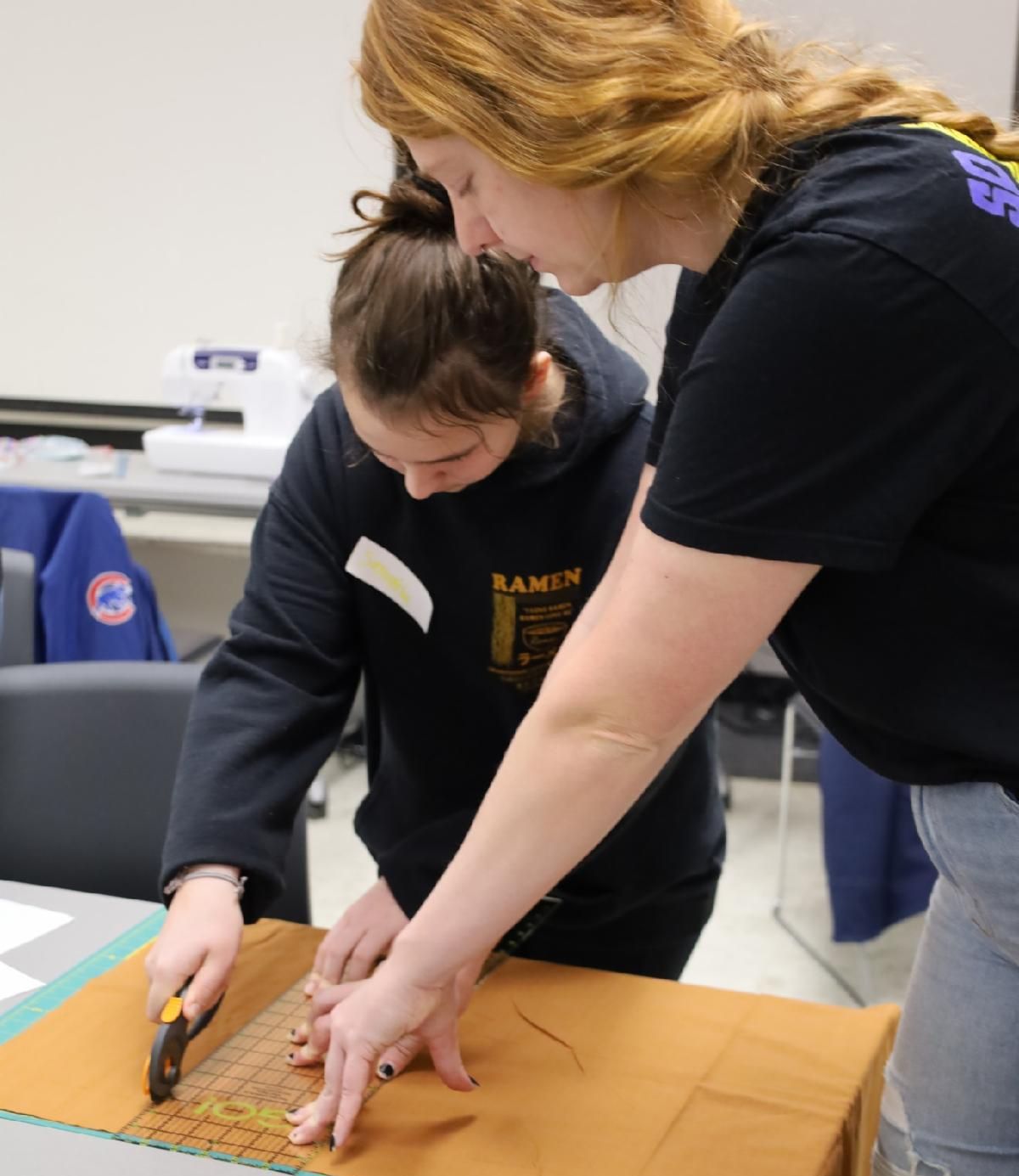 two girls cutting fabric on a table