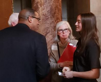 woman with folder watching man and teen girl talking
