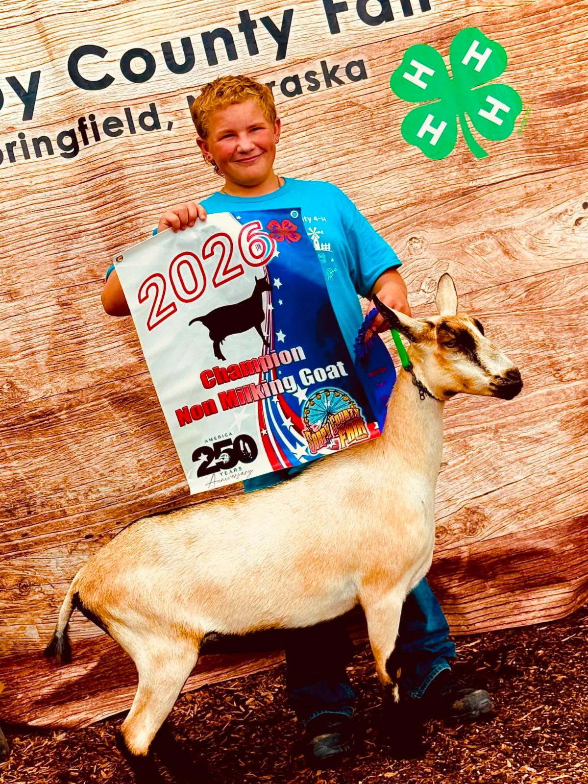 boy and goat holding a banner that says  2026 fair 