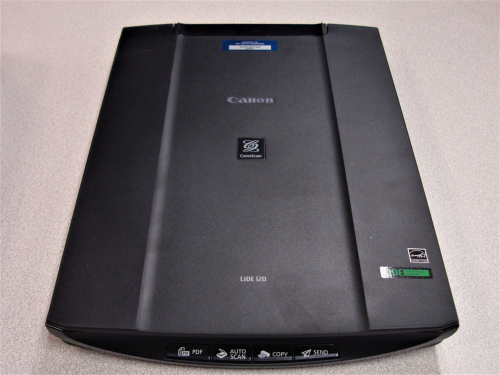 A black, rectangular device, slightly larger than a piece of paper, with four buttons across the front. 