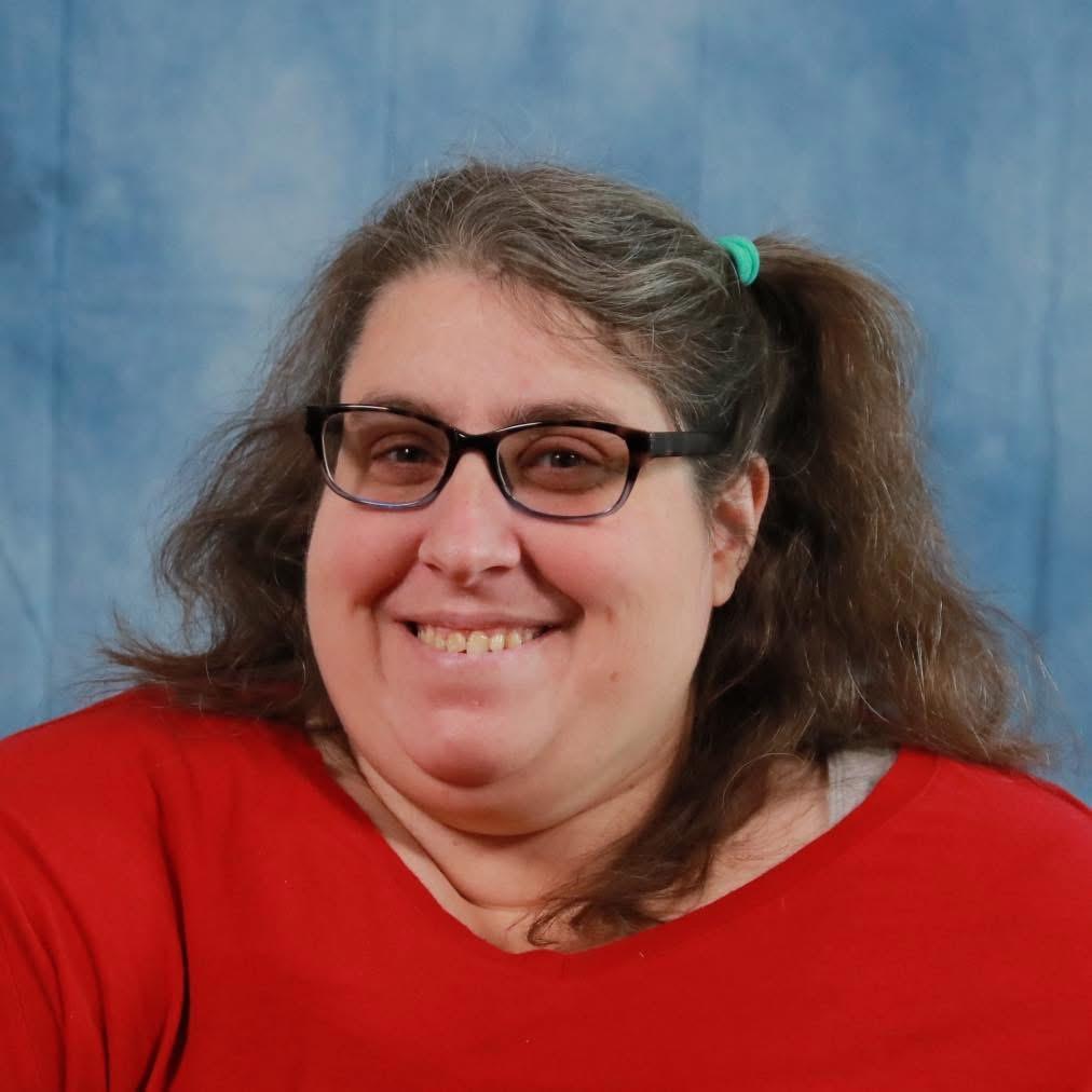 Alicia wearing glasses and a red shirt, smiling