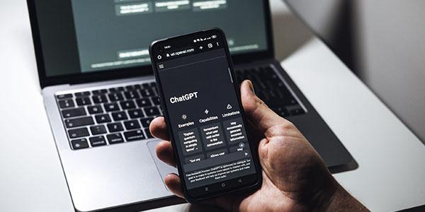 ChatGPT on phone held in front of laptop