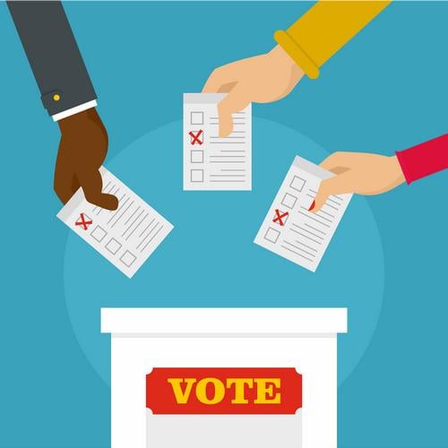 Hands with ballots putting them into a box with a label that reads Vote