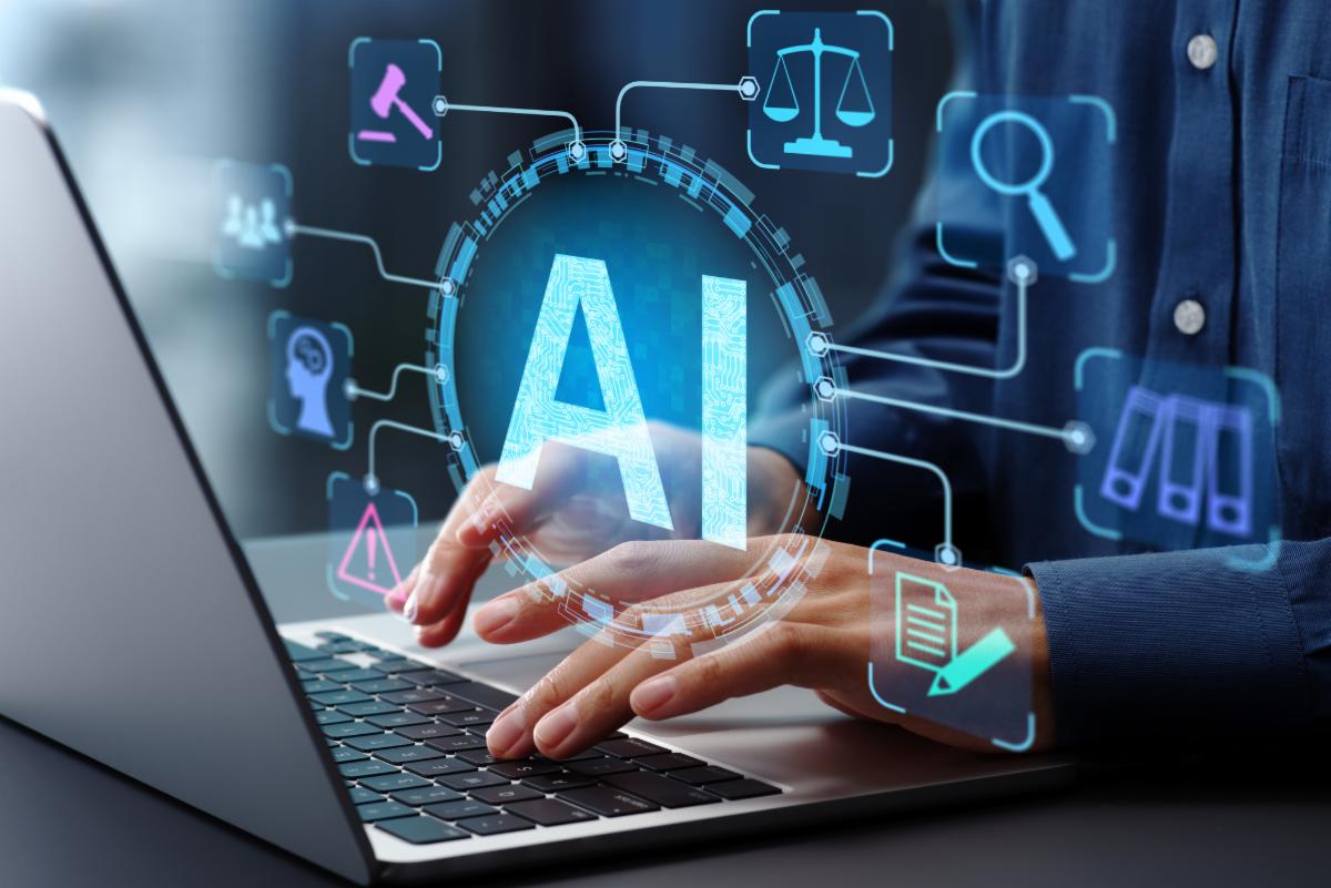 Hands typing on laptop.  The letters AI hover over the hands.