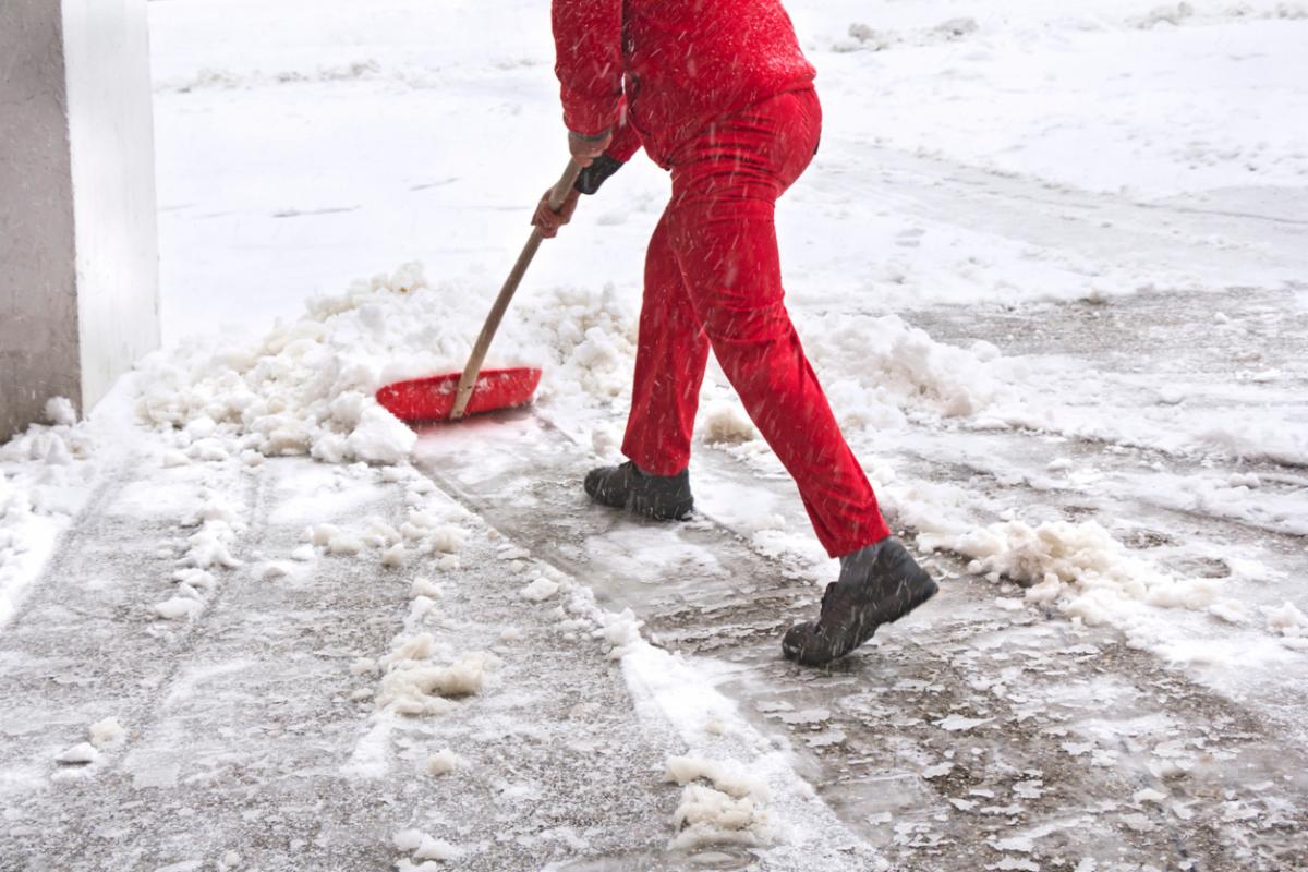 Business owner shoveling snow in front of building.
