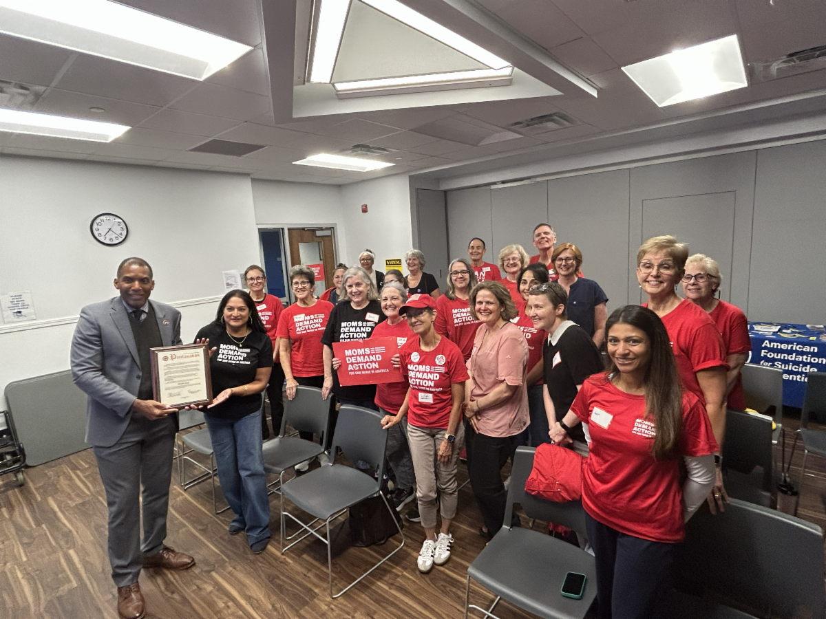 Group poses in meeting room with plaque. 