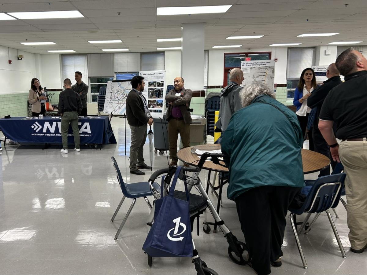 Community open house with people viewing displays and maps in a bright multipurpose room.