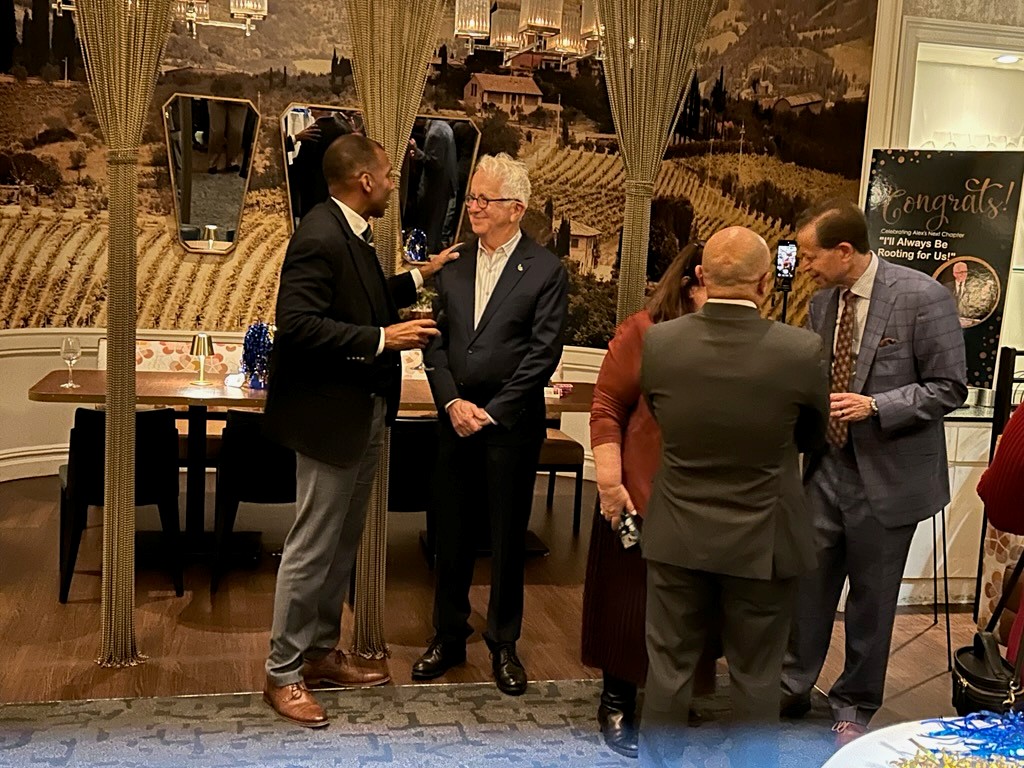 Two men stand and speak to each other. 