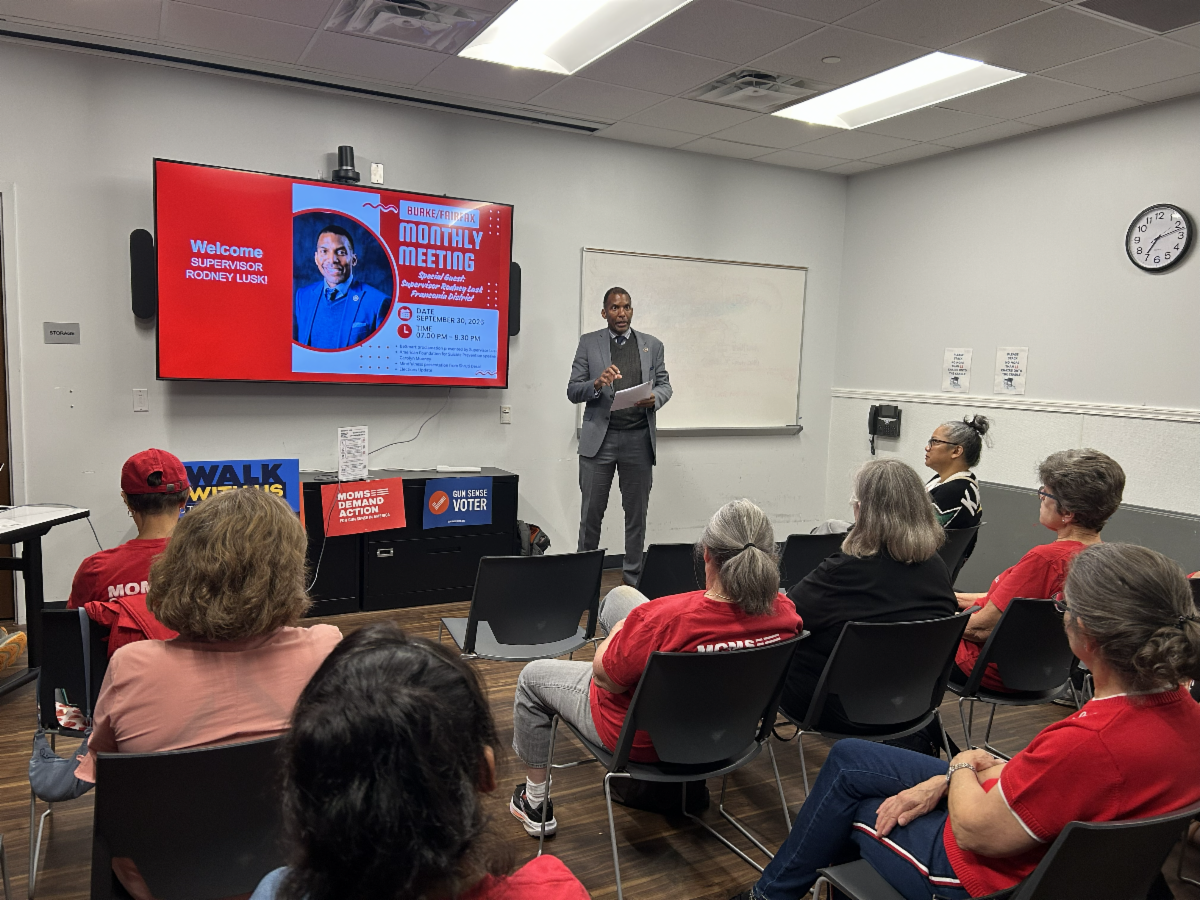Man gives presentation in front of group wearing red. 