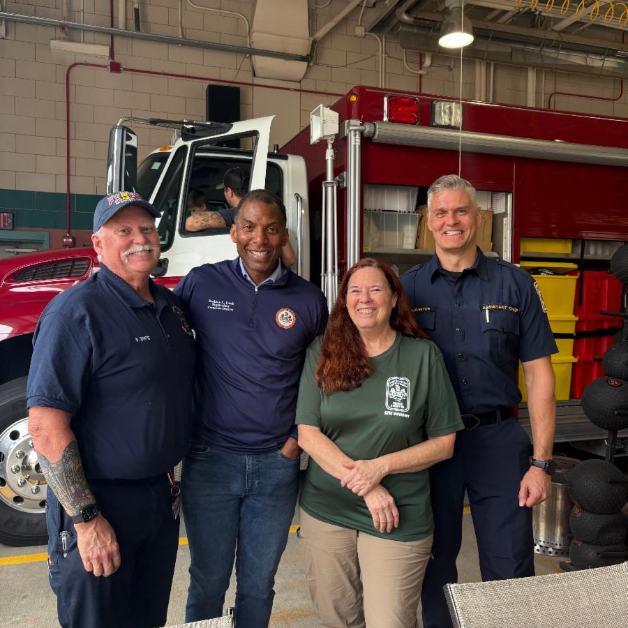 Four people pose in front of a fire truck.
