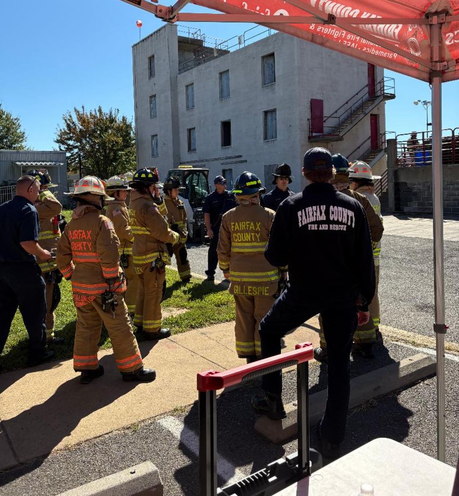 Group of firefighters stand near building.