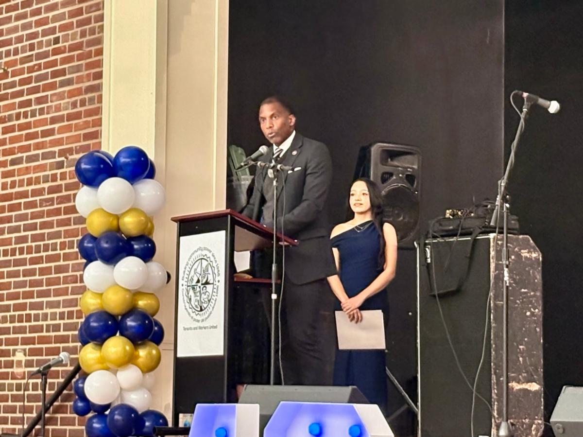 Man speaking at podium on stage.