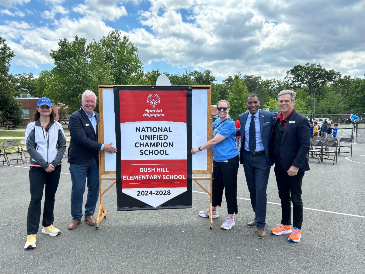 Adults posing on either side of a banner reading "National Unified Champion School Bush Hill Elementary School."