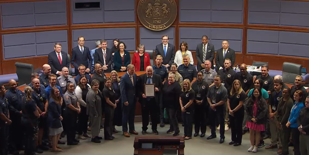 Group poses with plaque in auditorium. 
