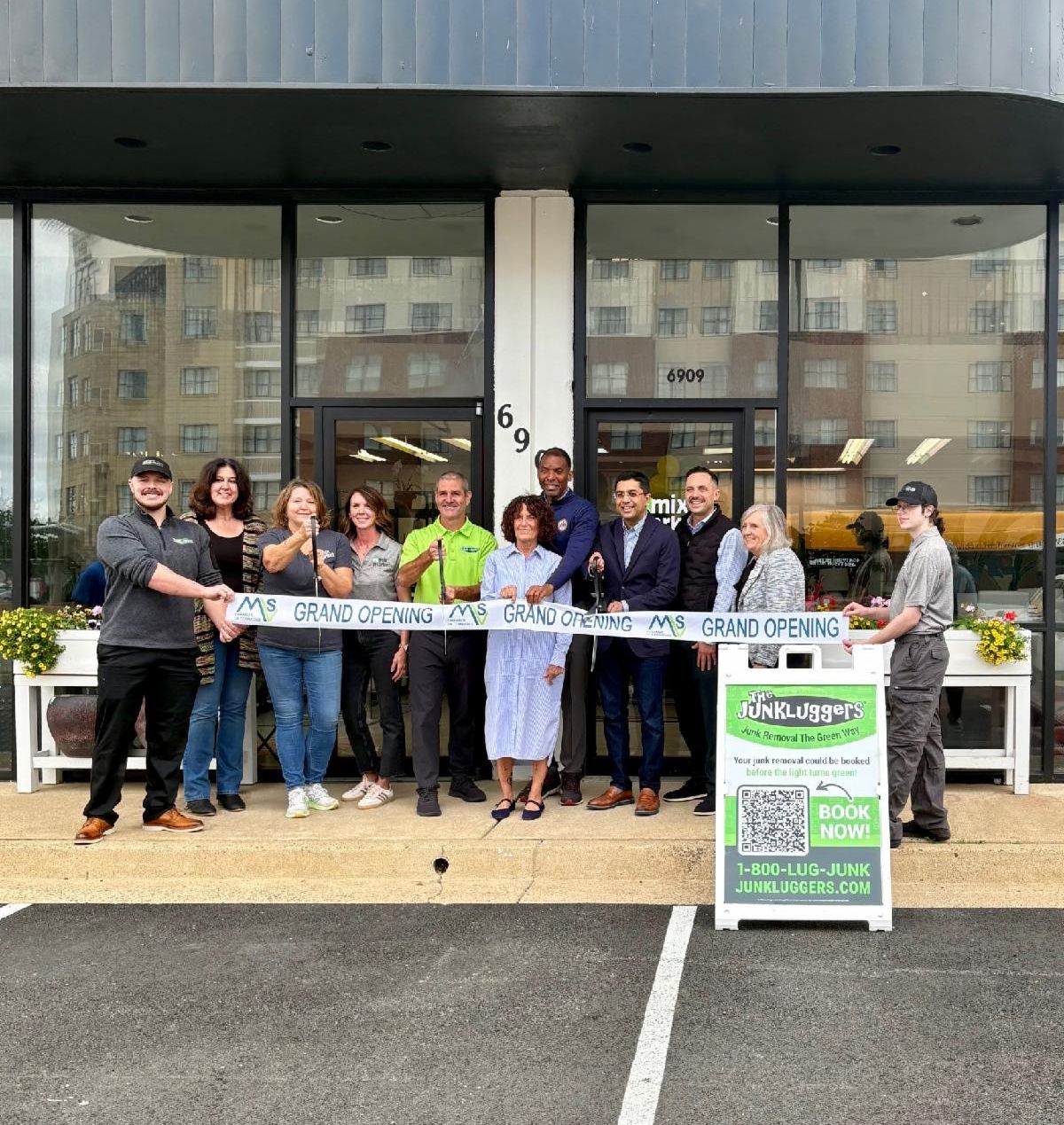 Group poses in front of building and cuts ribbon. 