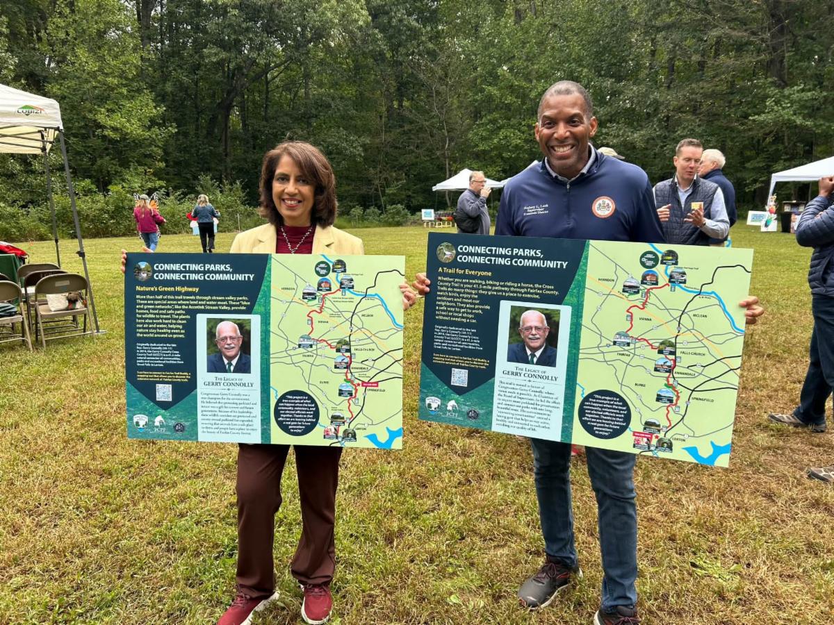 Two people pose with maps. 