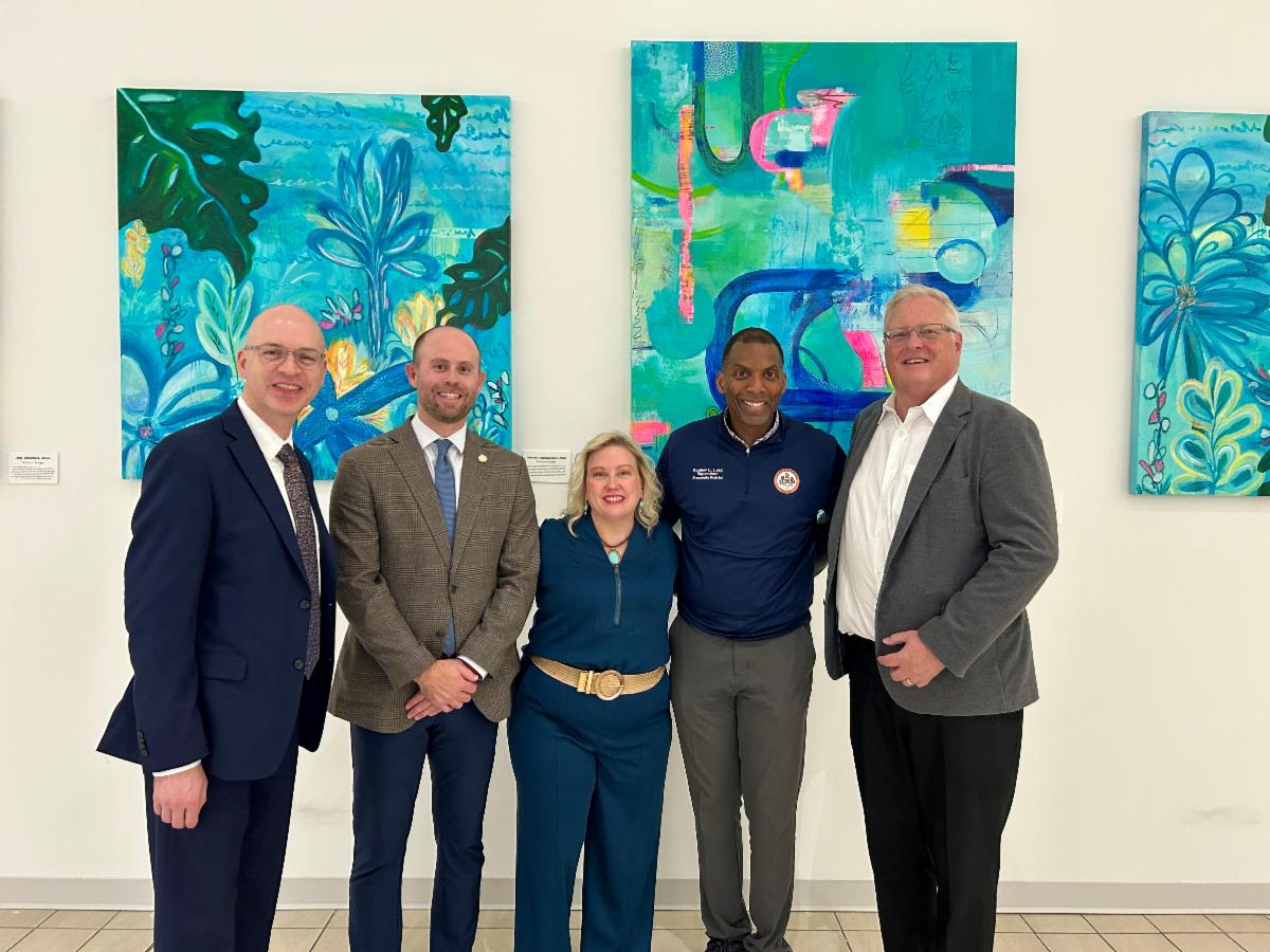 Group poses in front of hanging artwork.