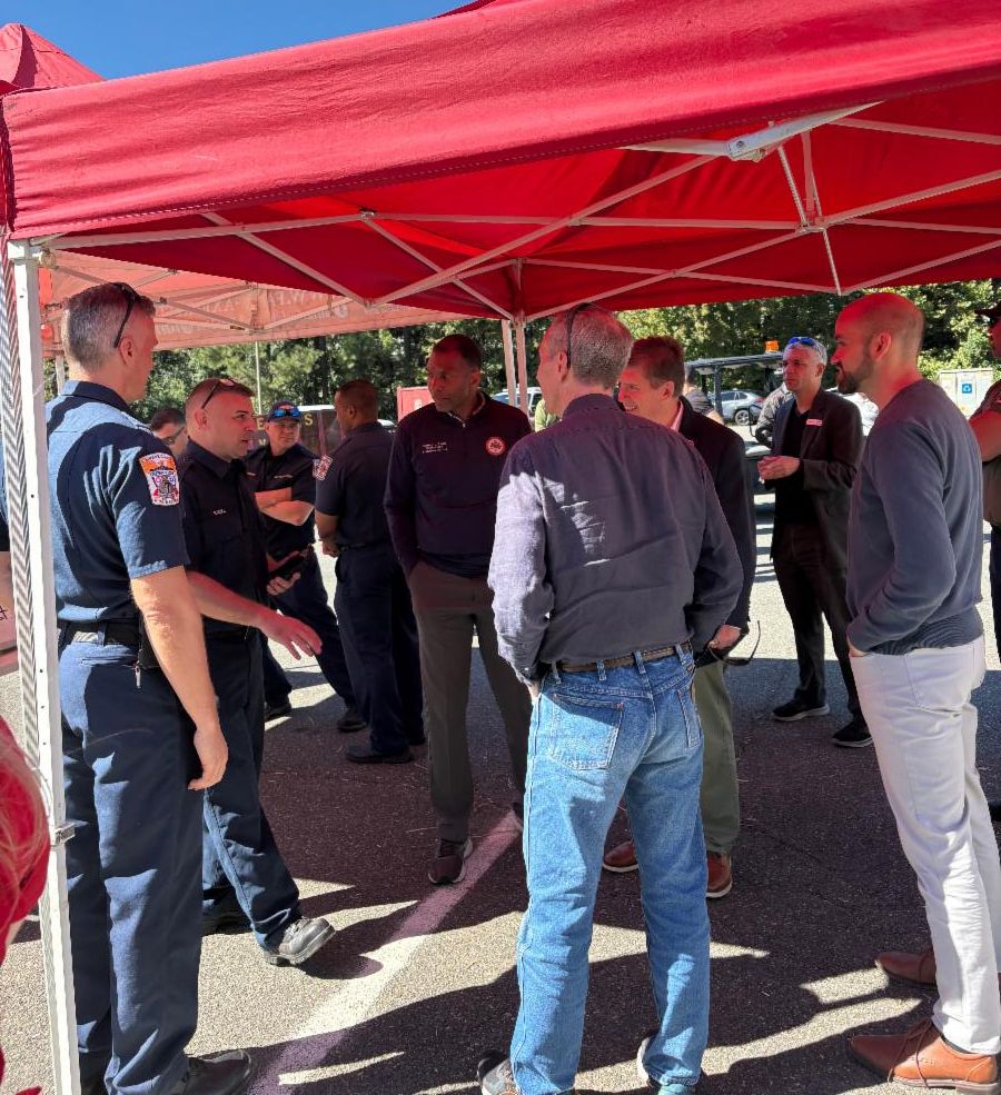 Group stands under red tent and talks.