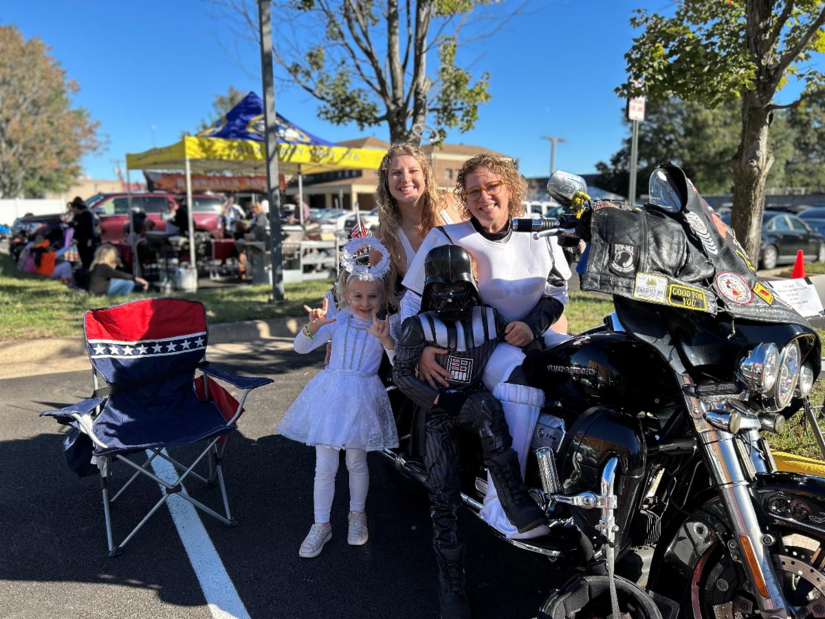 Family poses in Halloween costumes next to motorcycle. 