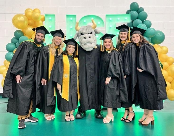 Graduates in cap and gown with USF Mascot Rocky the Bull
