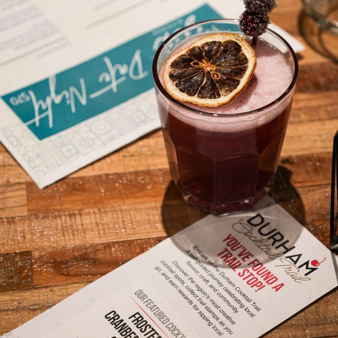 Cocktail on table with Durham Cocktail Trail pamphlets