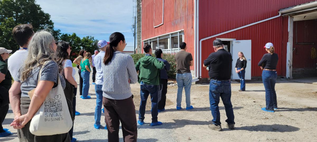 group of people standing outside a barn