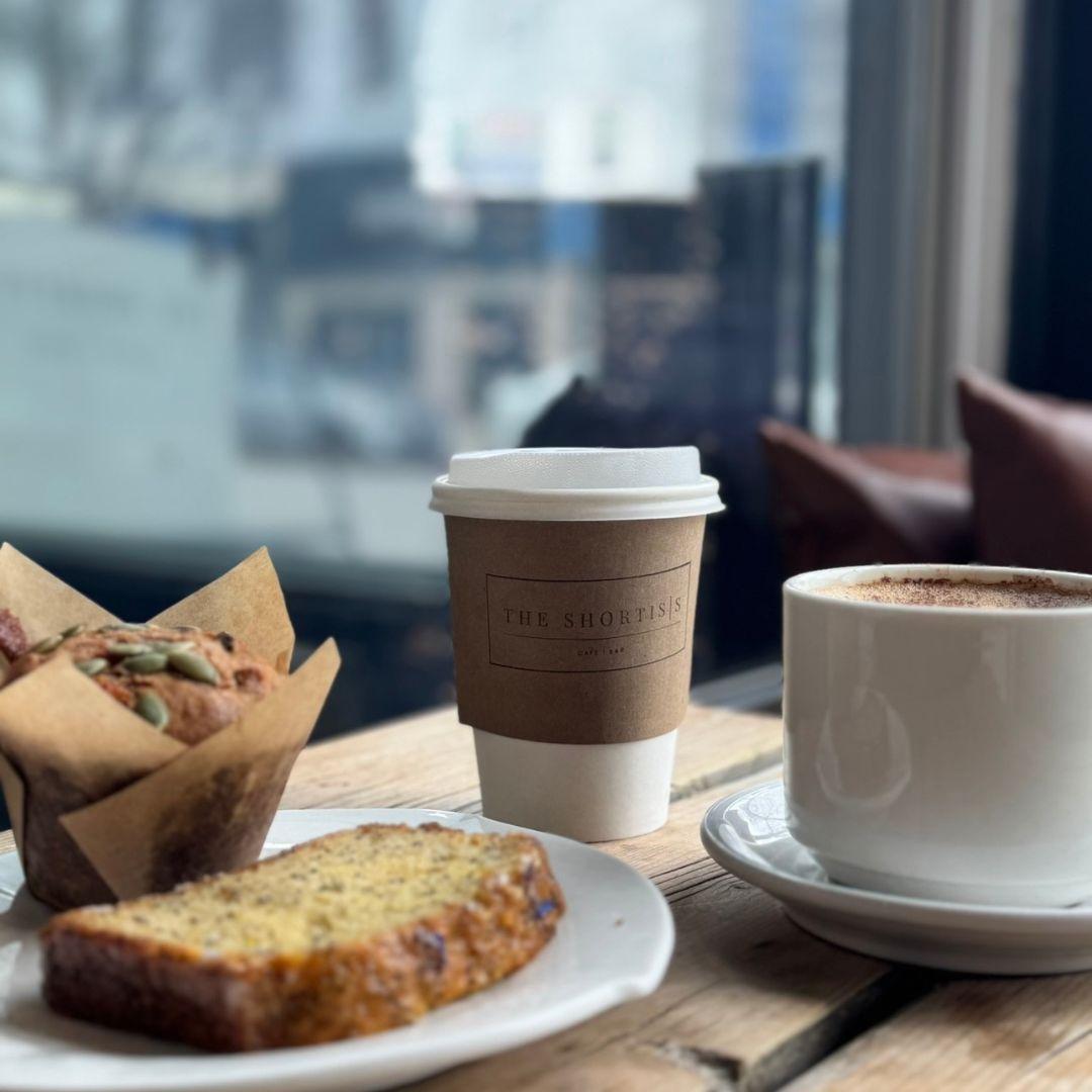 coffee in a cup and take out cup with muffin and bread on plate