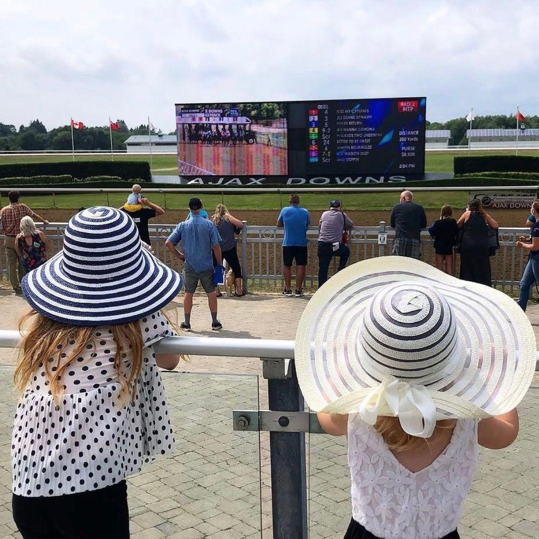 two children stand by the horse race track